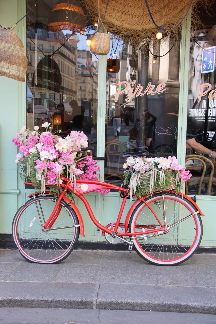 Vélo rouge fleuri devant la façade du café